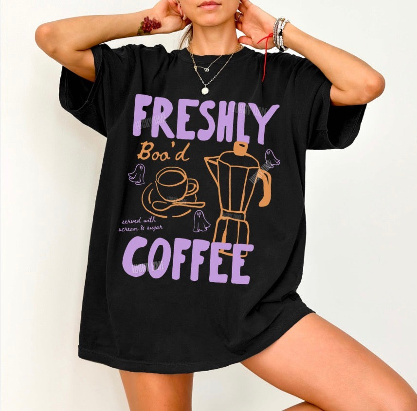 Person wearing a black t-shirt with colorful text and graphics on a plain background