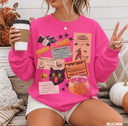A woman wearing a bright pink crewneck sweatshirt with a colorful Halloween-themed graphic collage, holding a coffee cup and posing with peace signs in an outdoor patio setting.
