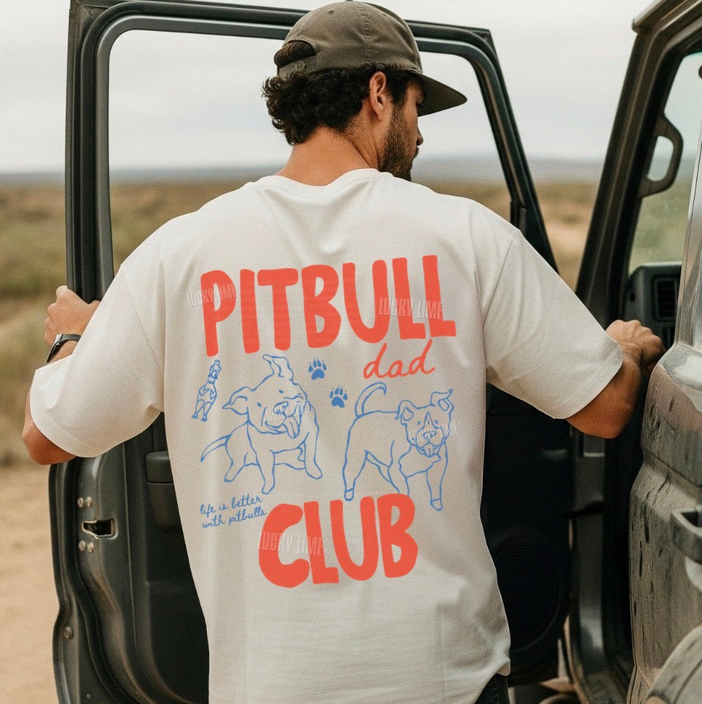 Man wearing a 'pitbull Dad Club' t-shirt getting into a vehicle in a desert setting.