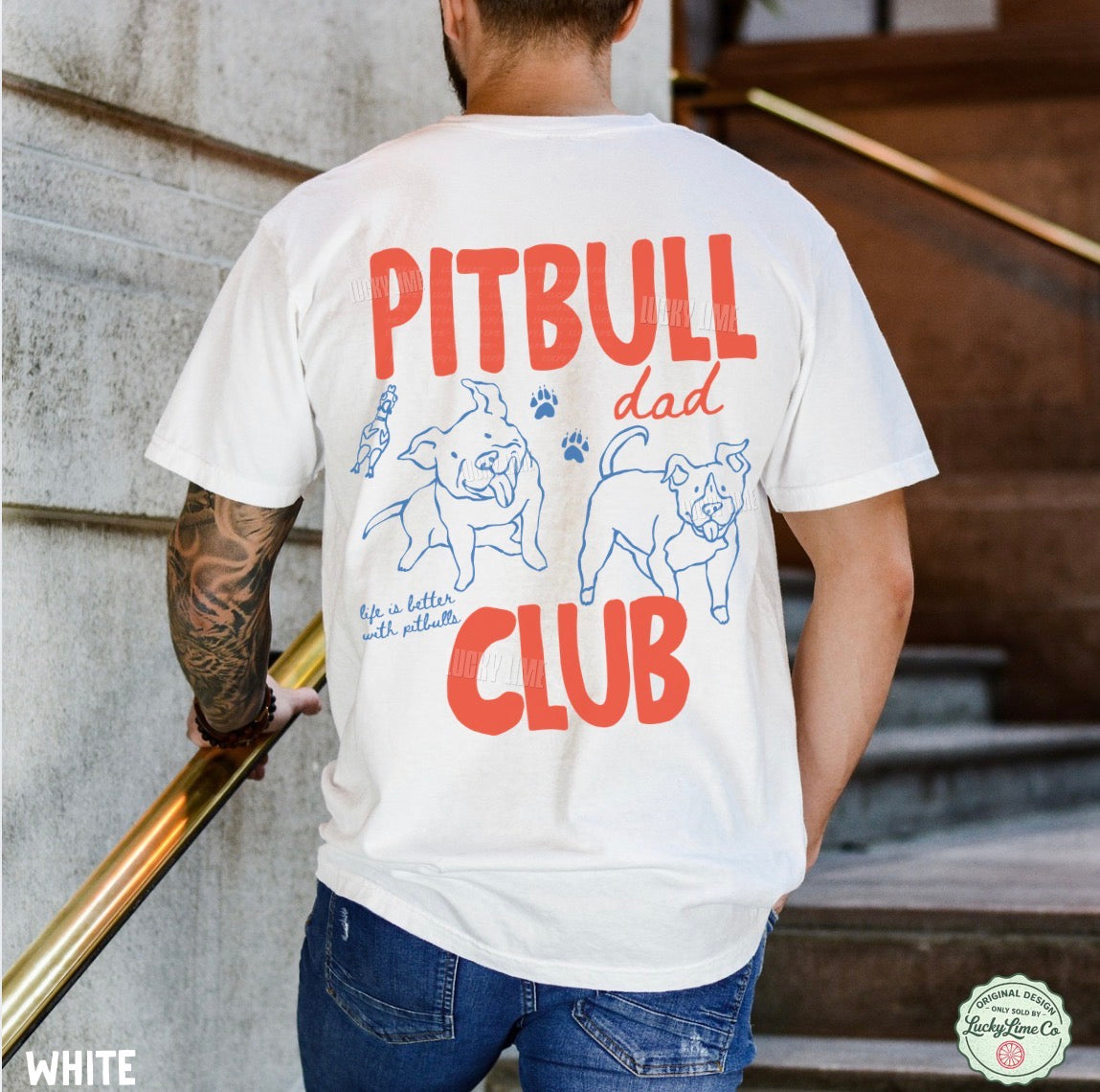 A man viewed from behind wearing a white graphic t-shirt with red and blue text and dog illustrations that read 'PITBULL dad CLUB'.