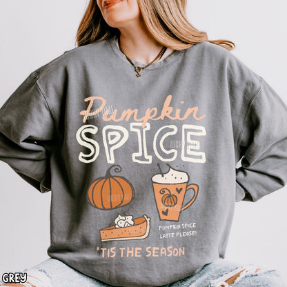 A woman wearing a gray oversized sweatshirt with a 'Pumpkin Spice' autumn graphic featuring a pumpkin, latte, and pie. The sweatshirt has a white and peach text design with a small 'GREY' label in the bottom-left corner.
