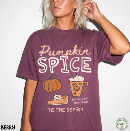 A woman wearing a berry purple graphic t-shirt with 'Pumpkin Spice' and autumn illustrations printed on the front, set against a plain white background.
