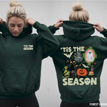 Two women modeling a forest green hoodie, showing both the front and back views. The front features the text 'IT'S THE SEASON' in a light yellow-green font.