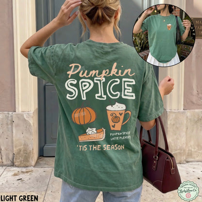 A woman stands outdoors wearing a light green graphic T-shirt from the back, with large 'Pumpkin Spice' text and fall-themed illustrations including a pumpkin, latte, and cinnamon toast. A circular inset shows the front of the shirt with a small pumpkin graphic.