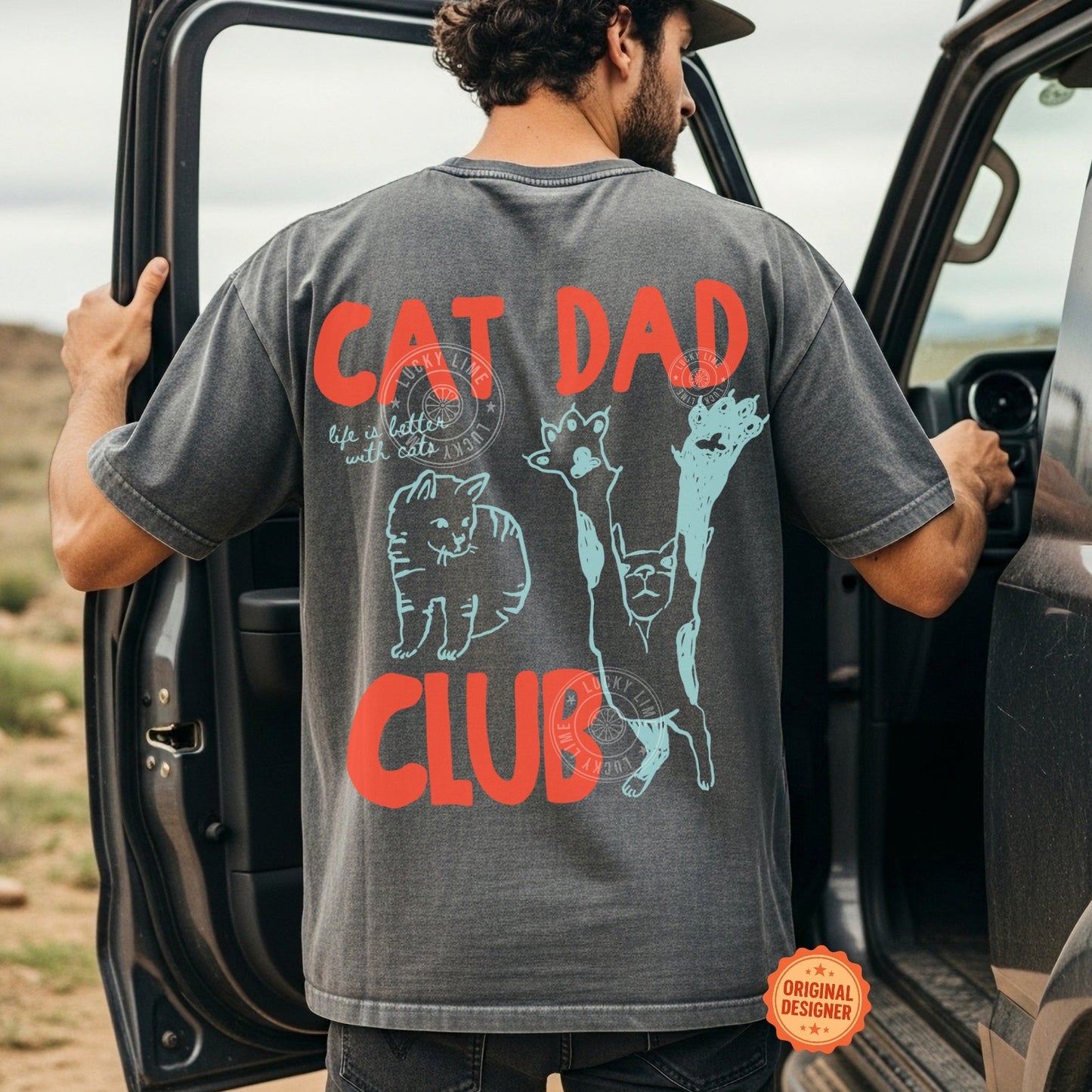 Man wearing a t-shirt with 'Cat Dad Club' design, standing next to a vehicle in an outdoor setting.