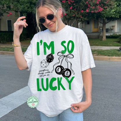 Person wearing a white t-shirt with green text saying ‘I’m So Lucky” and graphics, standing on a street.