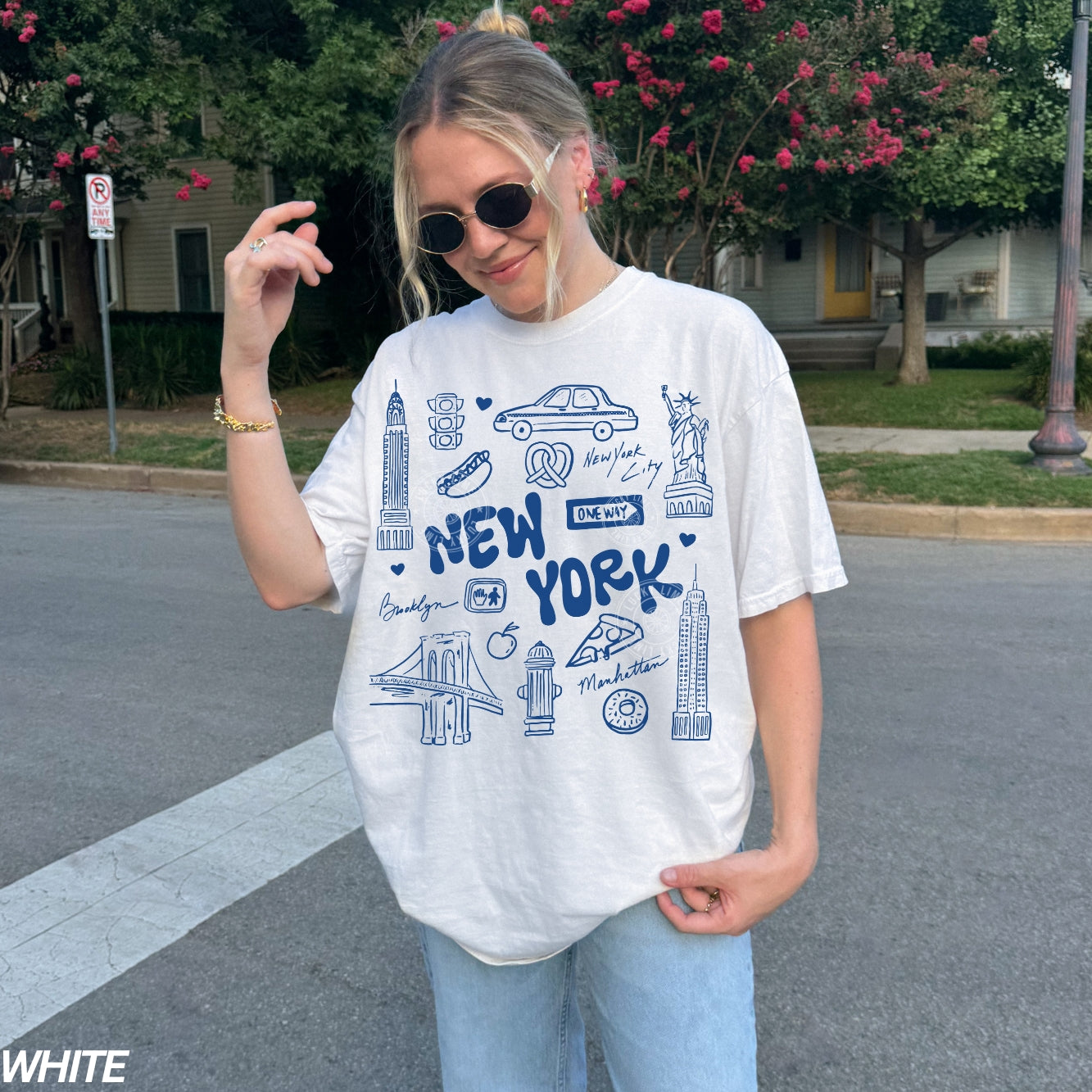 Person wearing a white t-shirt with 'New York' design outdoors.