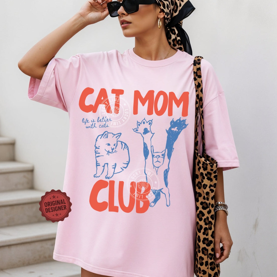 Woman wearing a pink t-shirt with 'Cat Mom Club' design, holding a leopard print bag.
