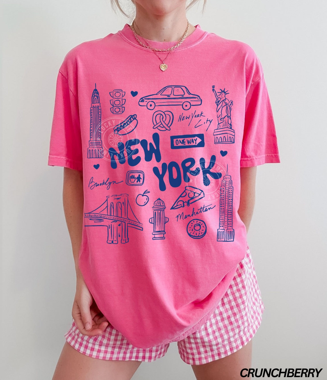 Person wearing a pink 'New York' t-shirt and checkered shorts with.